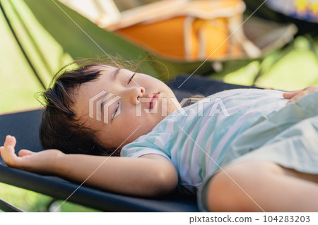 一個孩子來到露營地玩累了就睡在小床上 104283203