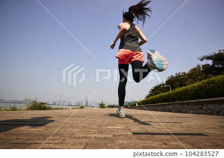 young asian adult woman running jogging outdoors, rear and low angle view young asian adult woman running jogging outdoors, rear and low angle view 104283527