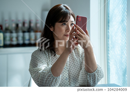 A middle-aged woman who is shocked to see a smartphone A middle-aged woman who is shocked to see a smartphone 104284009