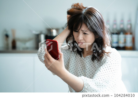 A middle-aged woman who is shocked to see a smartphone A middle-aged woman who is shocked to see a smartphone 104284010