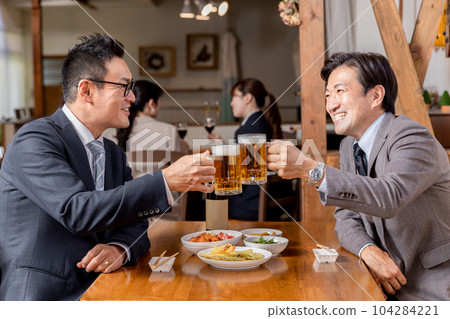 穿著西裝的商人/上班族在居酒屋與同事/朋友喝酒/舉杯啤酒 104284221