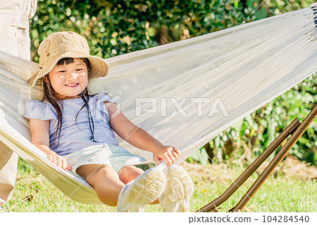 Child riding a hammock at an outdoor campsite (outside play) 104284540