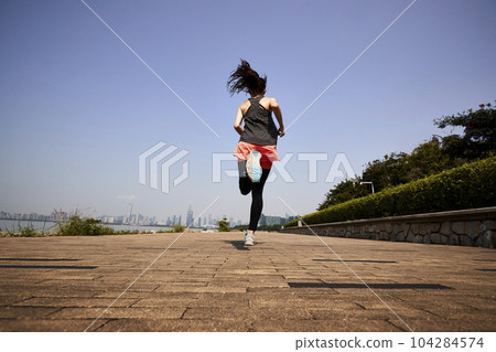 young asian adult woman running jogging outdoors, rear and low angle view 104284574