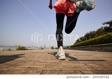 young asian adult woman running jogging outdoors, rear and low angle view young asian adult woman running jogging outdoors, rear and low angle view 104284582