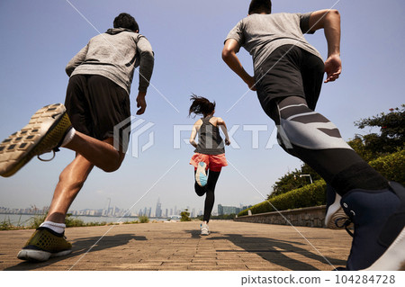 three young asian adults running jogging outdoors, rear and low angle view three young asian adults running jogging outdoors, rear and low angle view 104284728