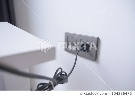 white color power cord cable plugged into wall white color power cord cable plugged into wall 104286476
