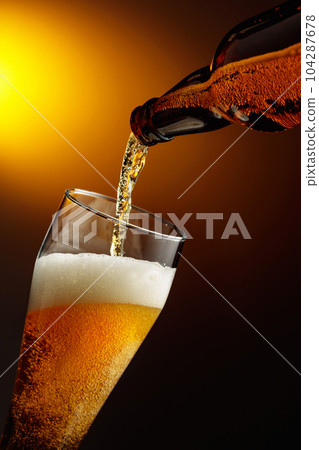 Pouring beer into a tall glass. 104287678