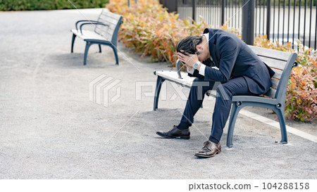 Worried businessman bench Worried businessman bench 104288158