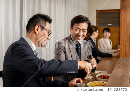 Smiling businessman serving a drink to his boss or colleague at the bar counter 104288770