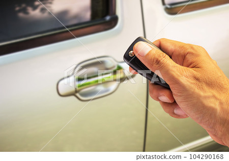 Man hand holding car key ready to start a new car with blurred car background.hand hold key blur car parking. 104290168