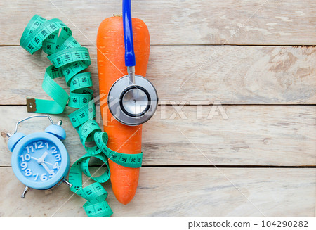 Top view carrot with blue stethoscope,measuring tape on wood table background. Top view carrot with blue stethoscope,measuring tape on wood table background. 104290282