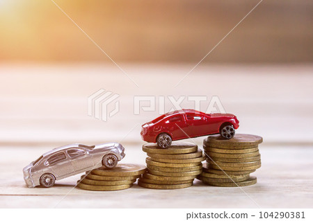Miniature toy car and coin money on wood table background with sunlight. Miniature toy car and coin money on wood table background with sunlight. 104290381