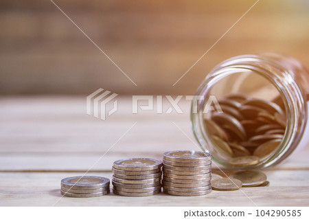 Close up saving money into a glass jar for cash in future investment. Close up saving money into a glass jar for cash in future investment. 104290585
