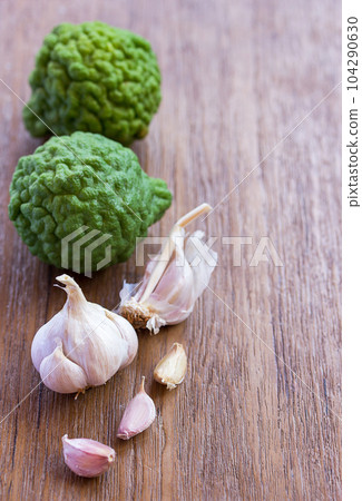 Top view of garlic and bergamot on wood table background with copy space for design. Top view of garlic and bergamot on wood table background with copy space for design. 104290630