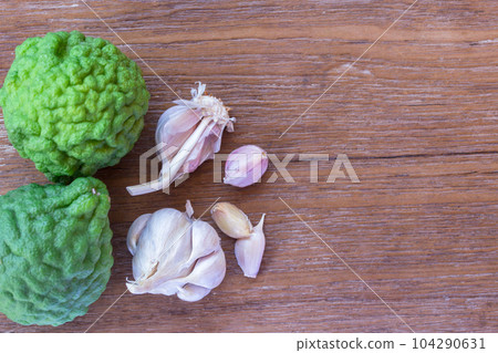 Top view of garlic and bergamot on wood table background with copy space for design. Top view of garlic and bergamot on wood table background with copy space for design. 104290631
