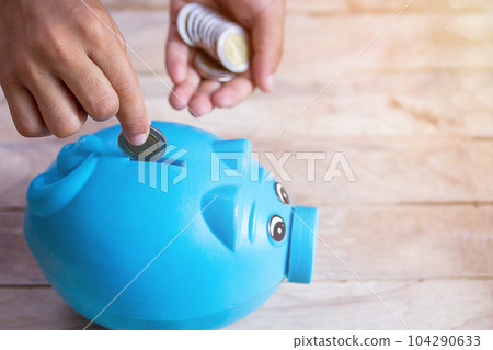 Business or finance saving concept with hand putting coin into blue piggy bank Business or finance saving concept with hand putting coin into blue piggy bank 104290633