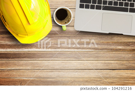 Yellow safety helmet and white paper on Brown old wood background Yellow safety helmet and white paper on Brown old wood background 104291216