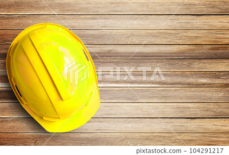 Yellow safety helmet and white paper on Brown old wood background 104291217