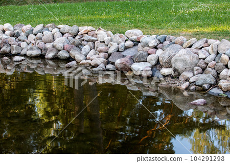 A shoreline reinforced with boulders. Erosion and landscaping 104291298