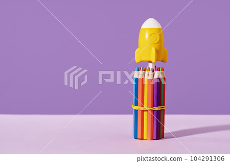 Yellow rocket stands on top of bunch of pencils. purple background. stationery with copy space for back to school or education and creativity concept. Success achievement and innovative ideas 104291306