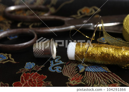 Spool of Gold Thread With Thimble on Vintage Black Silk Fabric Spool of Gold Thread With Thimble on Vintage Black Silk Fabric 104291866