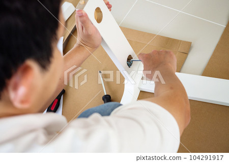 Man assembling white chair furniture at home Man assembling white chair furniture at home 104291917