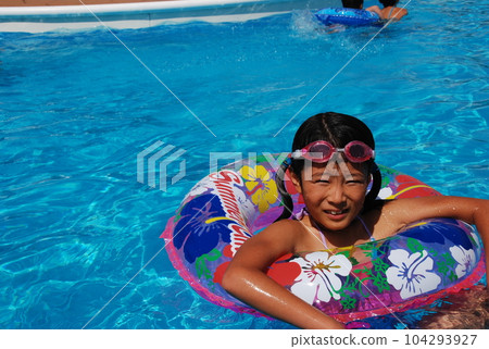 A cute girl playing in the pool of a resort hotel where she stayed on a family trip during summer vacation 104293927