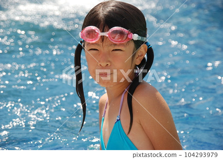A cute girl playing in the pool of a resort hotel where she stayed on a family trip during summer vacation 104293979