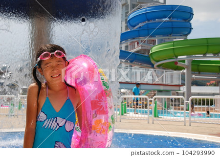 A cute girl playing in the pool of a resort hotel where she stayed on a family trip during summer vacation 104293990