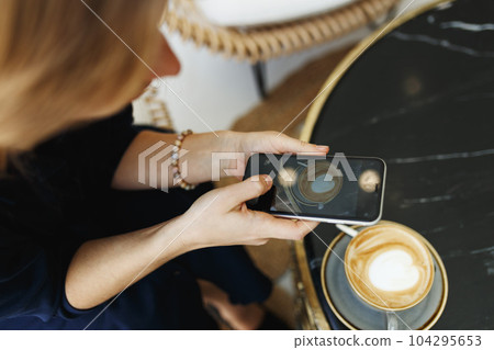 Woman taking photo of coffee with smartphone Woman taking photo of coffee with smartphone 104295653