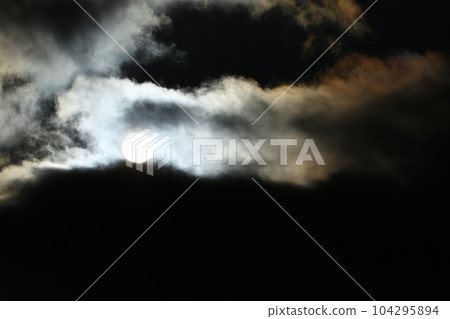 Sun disk behind backlit clouds 104295894