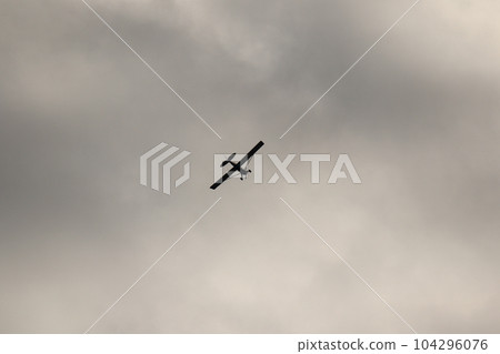 Small plane flying in the sky against dark clouds Small plane flying in the sky against dark clouds 104296076