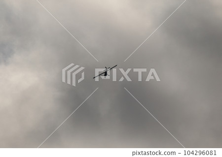Small plane flying in the sky against dark clouds 104296081
