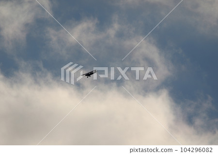 Small plane flying in the sky against dark clouds 104296082