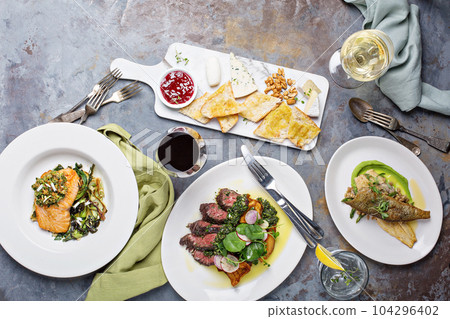 Big dinner table overhead view with steak and fish Big dinner table overhead view with steak and fish 104296402