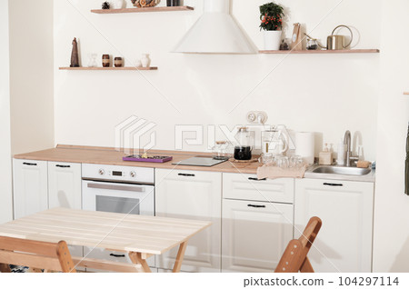 modern kitchen interior in apartment. trendy minimal style furniture with natural wood elements. white kitchen with decor, uncluttered and neat. 104297114