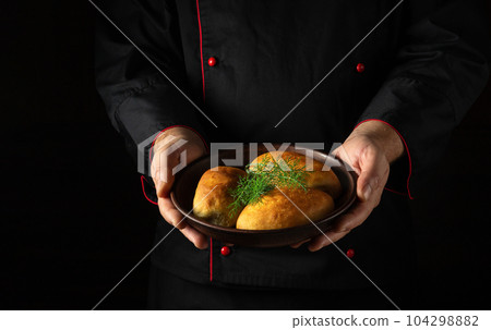 Pirozhki or pies with dill on a plate in the hands of the chef. Ukrainian national dish 104298882