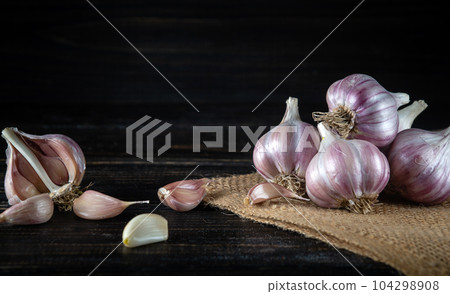 Garlic cloves on a black rustic table. Fresh peeled garlic and onions 104298908