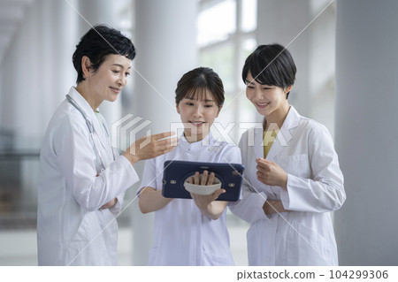 A female medical team having a meeting while looking at a tablet 104299306