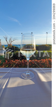 A glass of white wine on a table with a white tablecloth in an open-air cafe A glass of white wine on a table with a white tablecloth in an open-air cafe 104299869