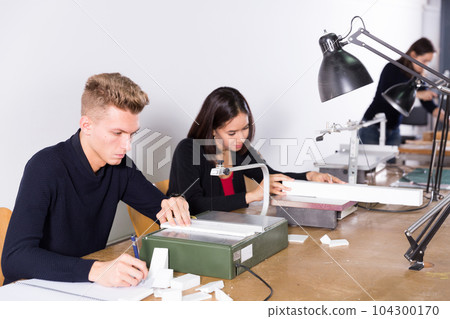 Young man working on scroll saw in architecture modeling workshop Young man working on scroll saw in architecture modeling workshop 104300170