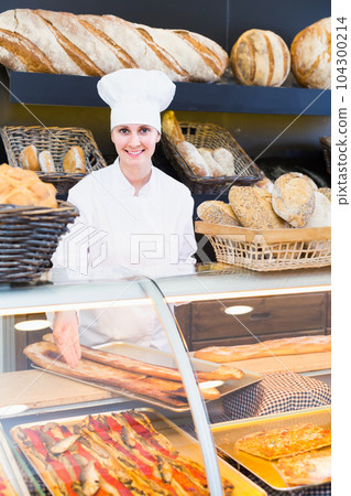 Portrait of young female bakers with tasty bread with fish smiling in bakery 104300214