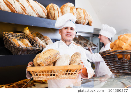 Employees offering bread in bakery 104300277