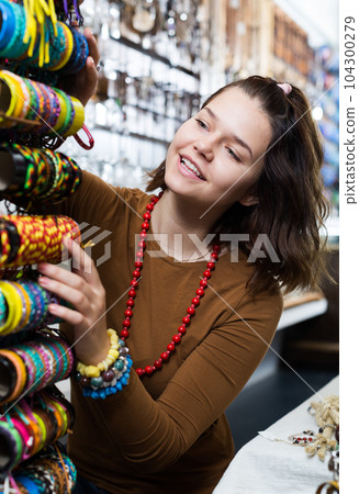 Girl seller offering colored bracelets 104300279