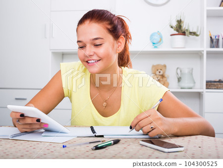 girl with smartphone doing homework . girl with smartphone doing homework . 104300525