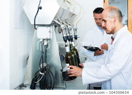 portrait of male winery worker with bottling machinery on factory portrait of male winery worker with bottling machinery on factory 104300634