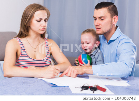 Sad woman with crying boy signing documents 104300748
