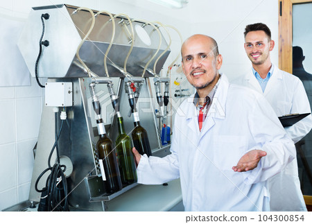 Man employee testing bottling equipment on facility Man employee testing bottling equipment on facility 104300854