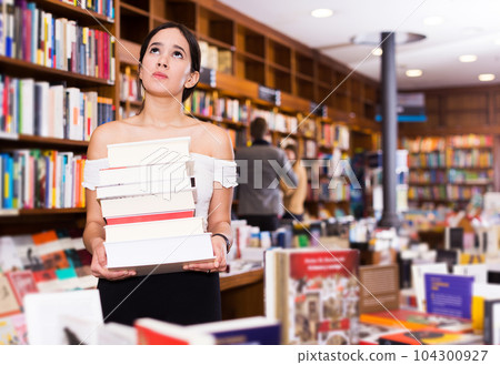 Sad girl holding pile of books 104300927
