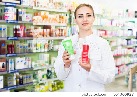 Young female is welcoming and holding medicines in hall of apothecary. Young female is welcoming and holding medicines in hall of apothecary. 104300928